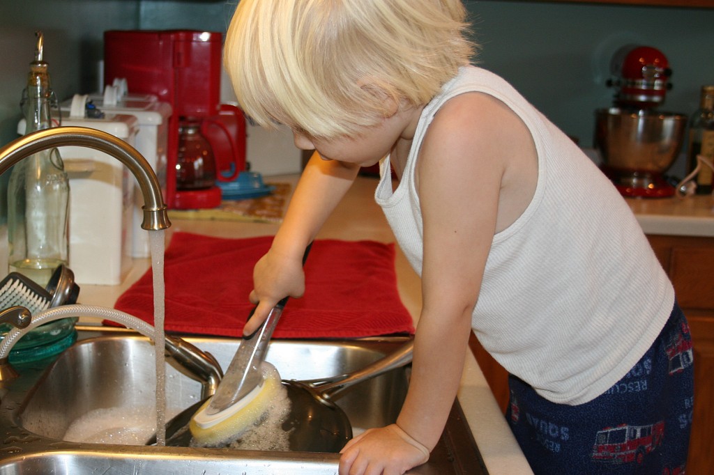 A little boy washing dishes